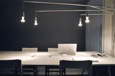 a white table with four chairs and two laptops on it in a dark room