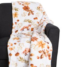 a chair with a blanket on it that has flowers and leaves all over the seat