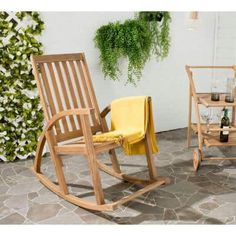 two wooden rocking chairs sitting next to each other on a stone patio with potted plants in the background