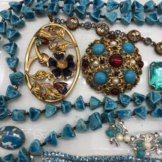 several necklaces and brooches laid out on a white surface with blue beads