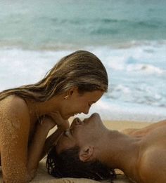 a man and woman laying on top of a sandy beach