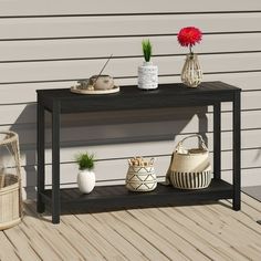 a black table with some plants and baskets on it next to a white house wall