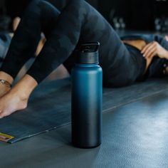 a woman laying on the floor with her legs up and holding onto a water bottle