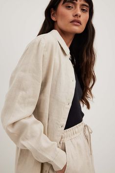 This shirt features a classic collar. It has long sleeves with a single button cuff and a chest pocket. Classic Long Sleeve Blouse With Roll-up Sleeves, Casual Beige Tops With Roll-up Sleeves, Single Breasted Relaxed Fit Linen Top, Classic Collared Shirt For Fall, Business Casual Blouse With Lapel Collar, Classic Long Sleeve Tops For Everyday, Casual Lapel Collar Blouse For Business, Casual Blouse With Lapel Collar For Business, Casual Tops With Hidden Button Closure For Fall