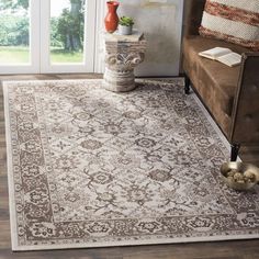 an area rug with a brown and white design on the floor in front of a couch