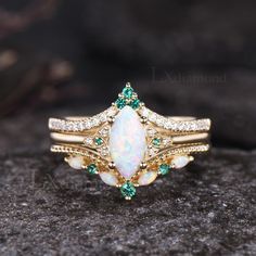 an opal and diamond ring on top of a rock with green crystals around it