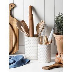 kitchen utensils and wooden spoons in white ceramic containers