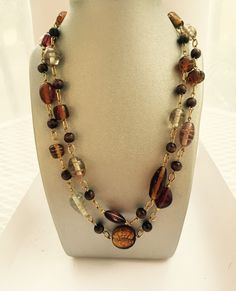 This necklace brings warmth to any look. It can be worn as a single long necklace or a wrap it around as it is a 40" long necklace.  It features acrylic, wood and glass beads. Brown Glass Necklace For Gift, Handmade Brown Necklaces For Layering, Adjustable Brown Multi-strand Long Necklace, Adjustable Multi-strand Brown Long Necklace, Glass Beaded Chain Long Necklace, Brown Single Strand Long Necklace, Brown Glass Beaded Necklaces For Gifts, Brown Glass Beaded Necklaces As Gift, Brown Double Strand Beaded Necklace For Gift