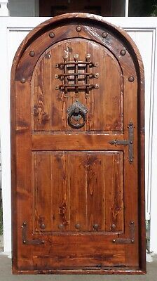 an old wooden door with metal hardware on the top and bottom, in front of a white building