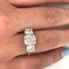 a woman's hand with three stone engagement ring on top of her left hand