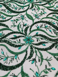 an embroidered fabric with green beads and leaves