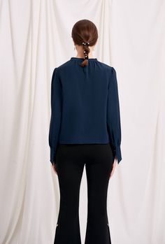 Everyone's favourite modern vintage style Buvette Pearl blouse now updated in a midnight-blue hue, featuring gently puffed sleeves, french cuffs and our signature pearl embellishment at the collar. Wear yours with a neutral coloured bottom and a bold red lip. Fabric: Soft, smooth and medium weight on the skin. Machine wash gentle (remove pearl) or hand wash. 100% Viscose. Fit Details: Relaxed fit. Fits true to size. Model measures 5'4", weighs 96 lbs and is wearing XS. Luxury Classic Navy Tops, Luxury Navy Tops For Workwear, Luxury Light Blue Tops For Business Casual, Luxury Feminine Tops For Workwear, Luxury Blouse For Workwear, Luxury Stretch Top For Business Casual, Luxury Stretch Tops For Business Casual, Luxury Blue Office Blouse, Luxury Trendy Tops For Workwear