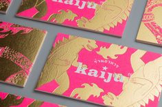 some pink and gold business cards on a gray surface