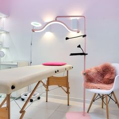 a chair and table in a room with lights on the wall above it, along with other furniture