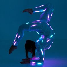 a woman in white is doing a handstand with neon lights on her body