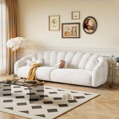 a living room with white couches and pictures on the wall above them, along with a coffee table