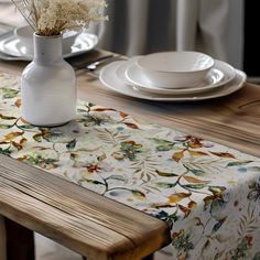 the table is set with white plates and flowers in a vase on top of it