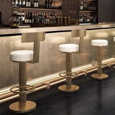 three white stools sitting in front of a bar