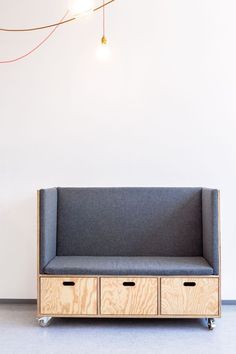 a gray couch sitting on top of a wooden shelf next to a wall mounted light