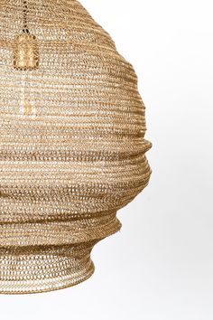 the light fixture is made out of woven material and has a gold colored metal frame