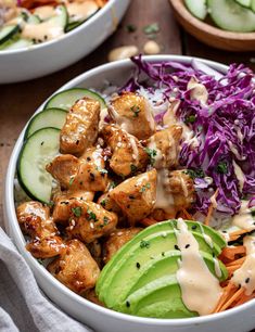 two bowls filled with chicken, coleslaw and cucumber