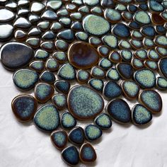 blue and green glass tiles are arranged on a white tablecloth with water drops in the middle