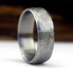 a wedding ring with an etched design on it's side, sitting on a white surface