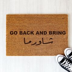 a door mat with the words go back and bring in arabic on it next to sneakers