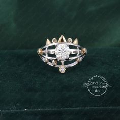 a gold and silver ring with an oval diamond in the center on a green velvet surface