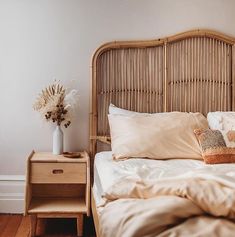 a wicker headboard in a bedroom next to a night stand with flowers on it