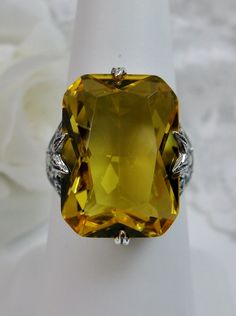 Simulated Lemon Citrine Ring Description Treasure Design#202 MADE TO ORDER This is a lovely Edwardian/Art Deco era reproductions ring. I now offer this lovely filigree reproduction in sterling silver. The simulated lemon yellow citrine is 18mm long by 13mm in width. The ring is 3/4th of an inch (19mm) NS (long) on the finger. The inside of the band is etched 925. Notice the intricate and detailed floral design of the antique patina silver filigree setting all the way down the band. This is an ex Yellow Citrine Ring, Mystic Fire Topaz, Floral Filigree, Edwardian Art, Gems Art, Yellow Citrine, Citrine Ring, Peridot Ring, Sterling Silver Filigree