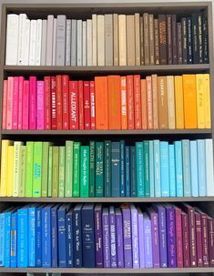 a book shelf filled with lots of books on top of each other and rainbow colored books