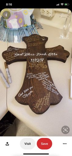 a wooden cross with writing on it sitting on a table next to some pens and paper