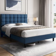 a bed with blue upholstered headboard and foot board in a white room