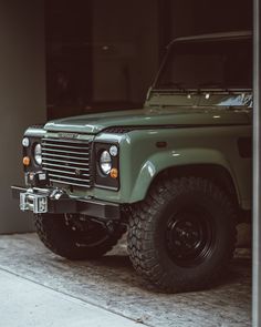 a green land rover parked in front of a building