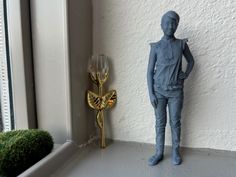 there is a small blue figurine next to a window sill with a gold clock on it