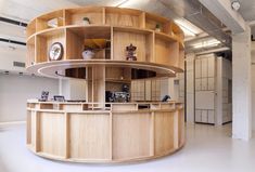 a circular wooden counter in the middle of a room with lots of shelves on it