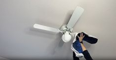 a person is hanging from the ceiling with a white ceiling fan in front of them