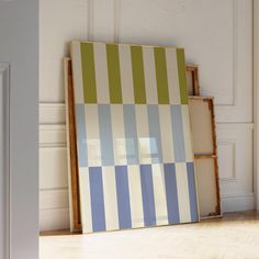 an empty room with a striped painting on the floor and a wooden frame in front of it