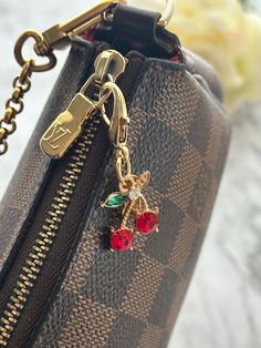 a close up of a purse with a keychain attached to it and flowers in the background