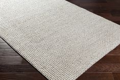 a white rug on top of a wooden floor with dark wood floors in the background