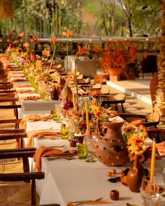 an outdoor dining area with tables and chairs covered in white tablecloths, vases filled with flowers