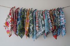 an assortment of colorful scarves hanging on a line with clothes pins attached to them