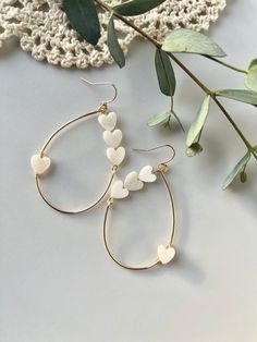 "Hearts-On-A-Wire earrings. The perfect addition to your Valentines Day outfit or any other day of the year!  Delicate shell, heart beads hand-wired on an 18k GF gold teardrop, wire hoop.  Part of our Minimal Lovey Line The Details: + 2.00\" long + Teardrop style + 18k Gold Filled + Shell heart beads  + Nickle Free + Lead Free" White Dangle Heart Earrings With Ear Wire, White Heart Beads Drop Earrings, White Drop Earrings With Heart Beads, White Pierced Earrings For Valentine's Day, White Valentine's Day Earrings, White Heart Bead Dangle Earrings, White Dangle Heart Bead Earrings, White Heart Beads Dangle Earrings, White Dangle Heart Earrings With Beads