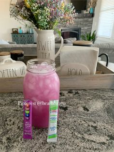 a pink drink sitting on top of a counter next to a vase filled with flowers