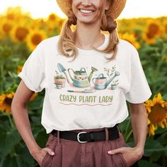 Introducing the "Crazy Plant Lady With Gardening Tools" t-shirt from Kooskadoo – the perfect gift for the green-thumbed goddess in your life! Crafted from premium Bella-Canvas fabric, this unisex tee is as soft and comfortable as it is stylish. With its playful yet chic design, featuring the words "Crazy Plant Lady" alongside charming gardening tools, this shirt is sure to delight any plant enthusiast. Whether she's tending to her beloved houseplants, cultivating a lush garden oasis, or simply e Green T-shirt With Plant Print For Gardening, Casual T-shirt For Gardening In Spring, Relaxed Fit T-shirt For Gardening In Spring, Casual Spring T-shirt For Gardening, Green Graphic Print T-shirt For Gardening, Short Sleeve T-shirt With Plants Print For Gardening, Cotton Graphic Print T-shirt For Gardening, Cotton T-shirt With Graphic Print For Gardening, Spring Short Sleeve T-shirt For Gardening