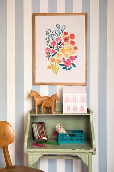 a small desk with a wooden toy horse on top of it next to a striped wall