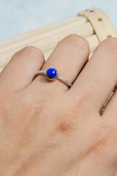 A pretty ring with a round central gemstone and signature rope detailing on the band, Bijoux adds a beautiful touch of glamour to your outfits. Handcrafted in solid sterling silver, Bijoux is perfect for stacking, showing us that simplicity is anything but boring. Style it alone or stacked with other rings to create your own personalized stack. Authentic Sivalya Lapis Lazuli Lapis Lazuli: Inner Power - Wisdom - Manifestation Hallmarked Metal: 925 Sterling Silver Gemstone Size: 5mm x 5mm Cut: Rou Minimalist Jewelry With Center Stone In Round Band, Sterling Silver Cabochon Rings, Minimalist Jewelry With Round Center Stone, Elegant Adjustable Birthstone Ring With Center Stone, Minimalist Round Center Stone Jewelry, Sapphire Sterling Silver Jewelry With Round Stone, Sterling Silver Jewelry With Bezel Setting, Sterling Silver Cabochon Promise Ring, Sterling Silver Birthstone Jewelry With Round Band