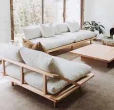 a living room with couches and tables in front of a large glass window that looks out onto the outdoors