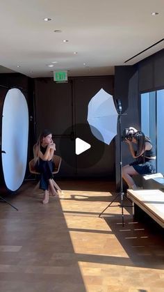 two women are sitting in front of surfboards on the floor and one is holding an umbrella